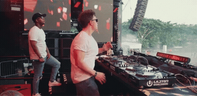 Two Men Playing Music In Front Of Ultra Worldwide Machine GIF