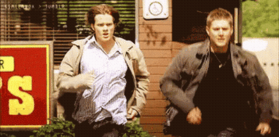 Two Men Running Past Sign 'S GIF