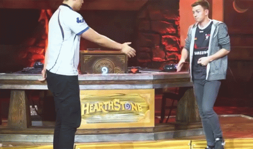 Two Men Shake Hands In Front Of A Hearthstone Sign GIF