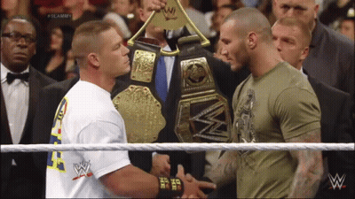 Two Men Shaking Hands In A Wrestling Ring With One Wearing A Shirt That Says ' I Am The One ' On It GIF