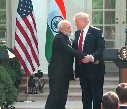 Two Men Shaking Hands In Front Of An American Flag And A Podium GIF