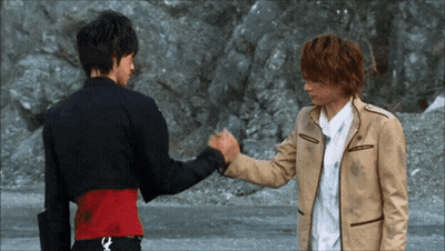 Two Men Shaking Hands In Front Of Rocky Cliff GIF