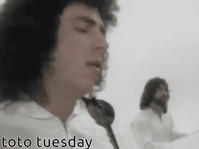 Two Men Singing In Front Of A White Background With Toto Tuesday In The Corner GIF