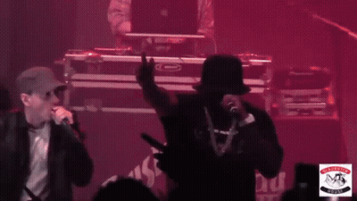Two Men Singing In Front Of Puck Sign GIF