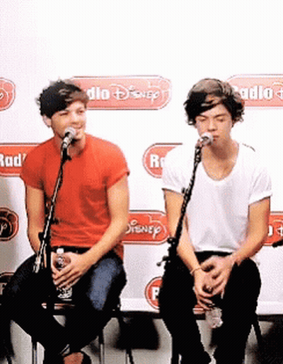 Two Men Singing Into Microphones In Front Of A Wall That Says Radio GIF