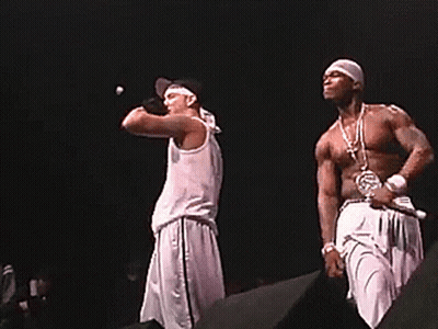 Two Men Singing Into Microphones On A Stage GIF