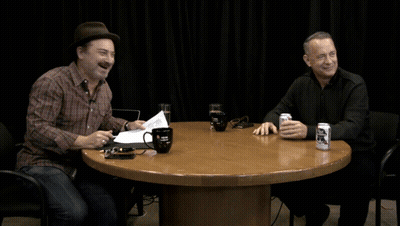 Two Men Sitting At A Table With A Can Of Bud Light GIF