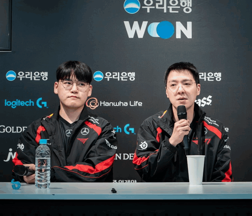 Two Men Sitting At A Table With A Sign That Says Won GIF