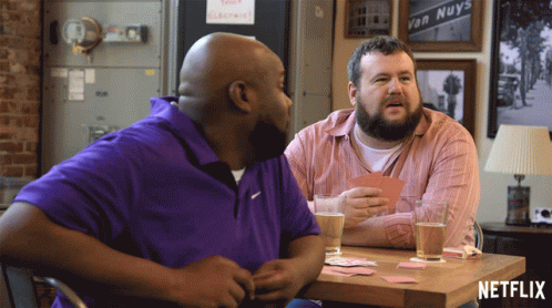 Two Men Sitting At Table With Netflix Logo GIF