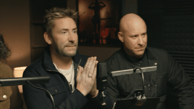 Two Men Sitting At Microphones With Hands Folded GIF