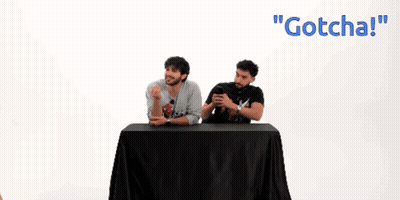 Two Men Sitting At Table One Wearing Gotcha Shirt GIF