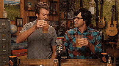 Two Men Sitting At Table Toasting Beer GIF