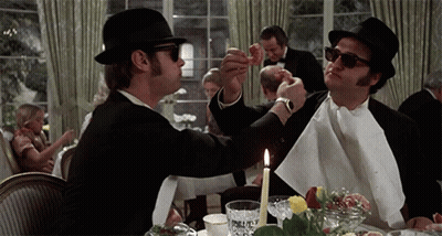 Two Men Sitting At Table With Candle And Napkin GIF