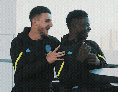 Two Men Sitting At Table With Emirates Sweatshirt GIF