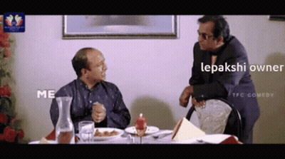 Two Men Sitting At Table With Food Lepakshi Owner GIF