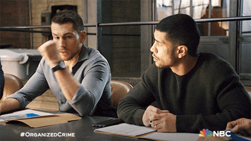 Two Men Sitting At Table With NBC Logo GIF