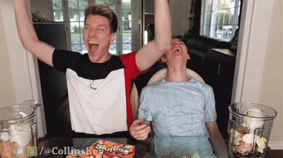 Two Men Sitting At Table With Skittles GIF
