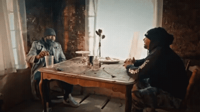 Two Men Sitting At Table With Supreme Sweatshirt GIF