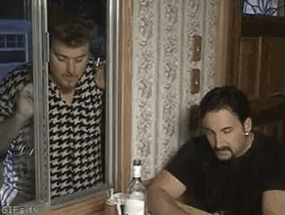 Two Men Sitting At Table With Vodka Bottle In Front Of Mirror GIF