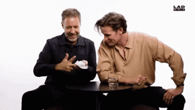 Two Men Sitting At Table With Water And Lad News Logo GIF