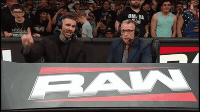 Two Men Sitting Behind Raw Sign GIF