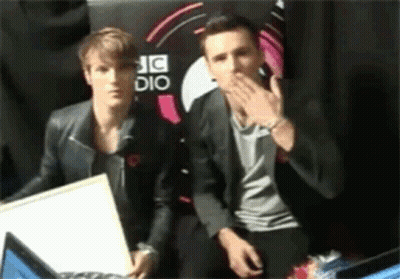 Two Men Sitting In Front Of A Sign That Says Dj Dio GIF