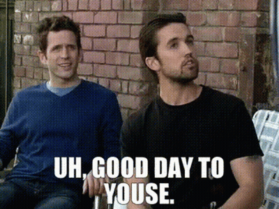 Two Men Sitting In Front Of Brick Wall Saying Uh Good Day To Youse GIF