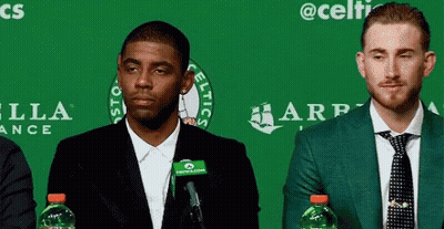 Two Men Sitting In Front Of Green Wall With Celtics GIF