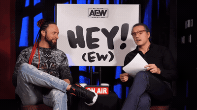 Two Men Sitting In Front Of Hey (Ew) Sign GIF