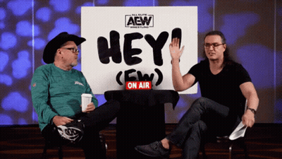 Two Men Sitting In Front Of Hey On Air Sign GIF