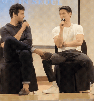 Two Men Sitting In Front Of Seoul Screen GIF