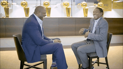 Two Men Sitting In Front Of Trophy Wall GIF