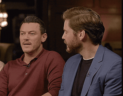 Two Men Sitting Next To Each Other One In Blue Suit GIF