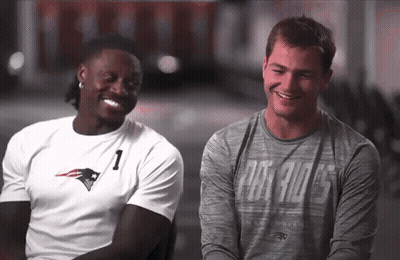Two Men Sitting Next To Each Other One Wearing Patriots Shirt GIF