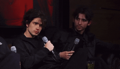Two Men Sitting Next To Each Other With Microphones GIF