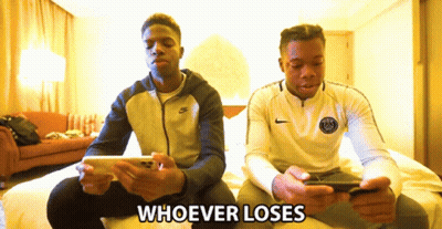 Two Men Sitting On A Bed Looking At Their Cell Phones With The Words Whoever Loses Behind Them GIF