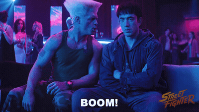 Two Men Sitting On A Couch With The Word Boom Written On The Bottom GIF