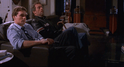 Two Men Sitting On A Couch With Their Feet Up GIF
