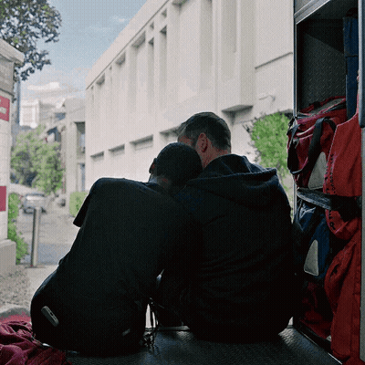 Two Men Sitting On Ambulance Heads Together GIF