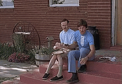 Two Men Sitting On Brick Steps Eating GIF