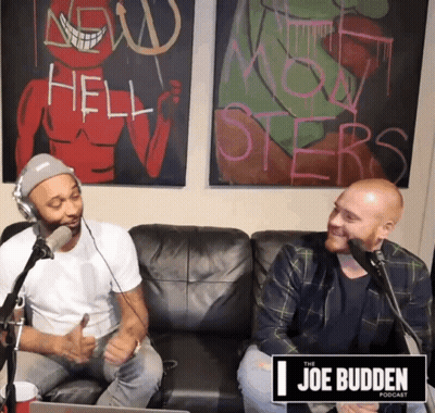 Two Men Sitting On Couch In Front Of Joe Budden Sign GIF