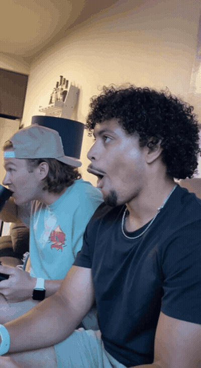 Two Men Sitting On Couch One In Top Hat One In Black Shirt GIF