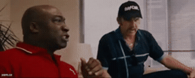 Two Men Sitting On Couch One Wearing Abercrombie Cap GIF