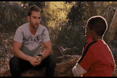 Two Men Sitting On Log Talking In Woods GIF