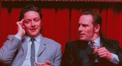Two Men Sitting One Holding Martini Glass GIF