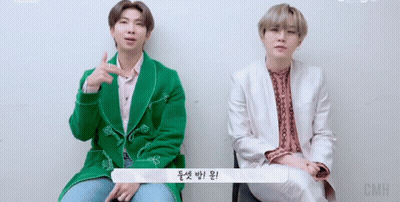 Two Men Sitting, One In Green Jacket GIF