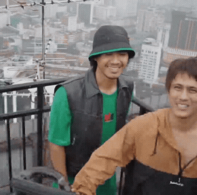 Two Men Smiling On Balcony GIF
