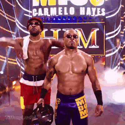 Two Men Standing Before Carmelo Hayes Sign GIF