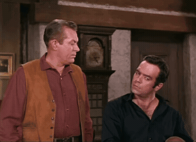 Two Men Standing Beside Large Clock GIF