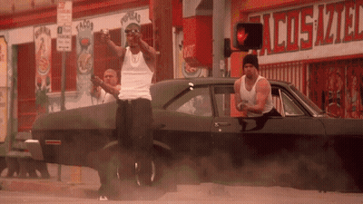 Two Men Standing By Car In Front Of Cosmo Store GIF